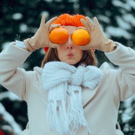 Femme en manteau d’hiver tenant des oranges pour booster son énergie en hiver