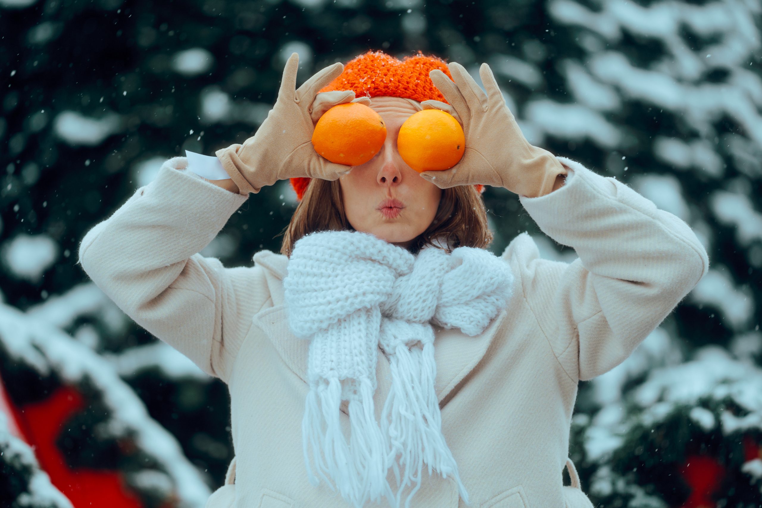 Femme en manteau d’hiver tenant des oranges pour booster son énergie en hiver